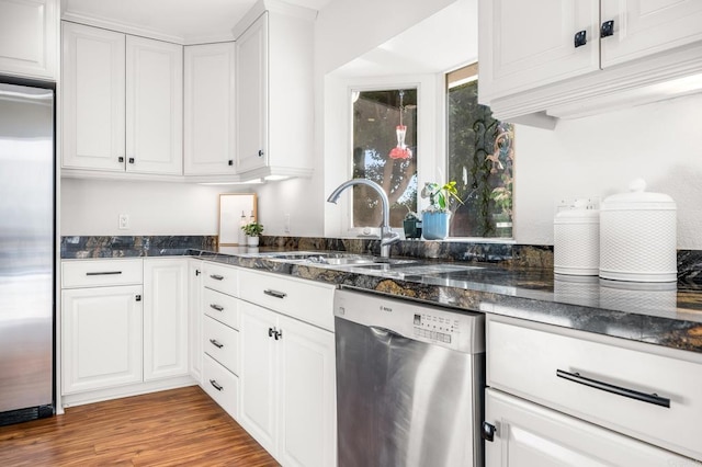 1592 Hawk View Dr, Encinitas, CA 92024 - kitchen with appliances with stainless steel finishes, white cabinetry, dark stone counters, and wood finished floors