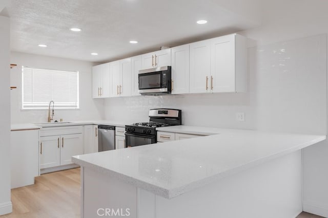 16233 Manzanita St, Hesperia, CA 92345 - kitchen with stainless steel appliances, a peninsula, light wood-style floors, white cabinets, and recessed lighting