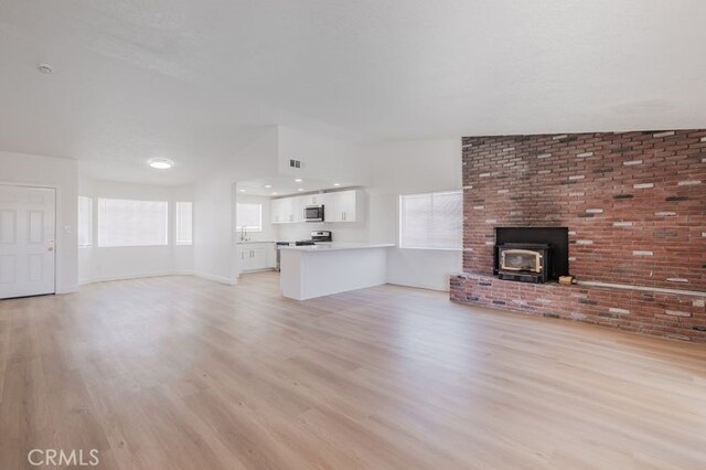16233 Manzanita St, Hesperia, CA 92345 - unfurnished living room featuring light wood-type flooring and a wood stove