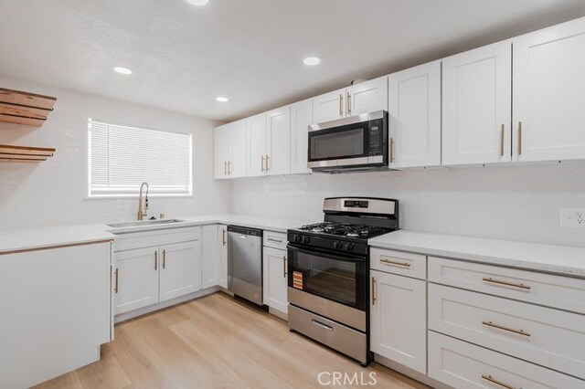 16233 Manzanita St, Hesperia, CA 92345 - kitchen with appliances with stainless steel finishes, white cabinets, light wood-style floors, light countertops, and recessed lighting