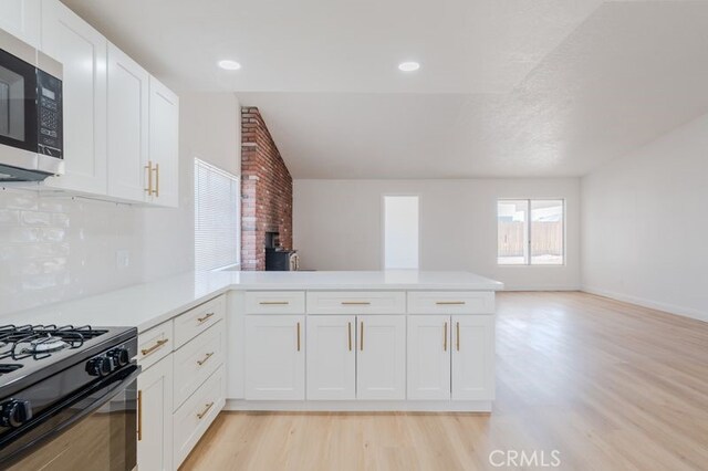 16233 Manzanita St, Hesperia, CA 92345 - kitchen with stainless steel microwave, a peninsula, light wood-type flooring, black range with gas cooktop, and light countertops