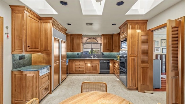 4968 Chapala Dr, Riverside, CA 92507 - kitchen with black appliances, a skylight, brown cabinets, decorative backsplash, and recessed lighting