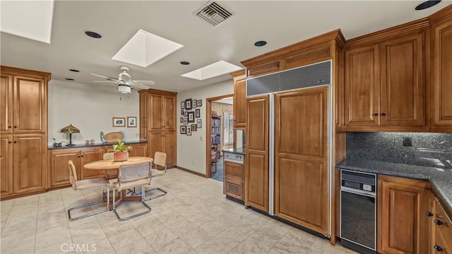 4968 Chapala Dr, Riverside, CA 92507 - kitchen with paneled fridge, a skylight, brown cabinets, a ceiling fan, and tasteful backsplash