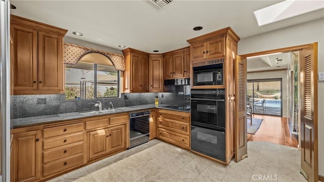 4968 Chapala Dr, Riverside, CA 92507 - kitchen with black appliances, a skylight, brown cabinets, decorative backsplash, and recessed lighting