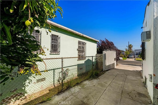 629 E 93rd St, Los Angeles, CA 90002 - view of side of property with stucco siding, a gate, and an AC wall unit