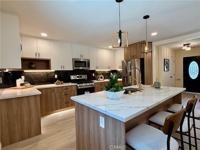 1319 Riedel Ave, Fullerton, CA 92831 - kitchen with stainless steel appliances, light wood finished floors, a kitchen bar, light stone counters, and recessed lighting