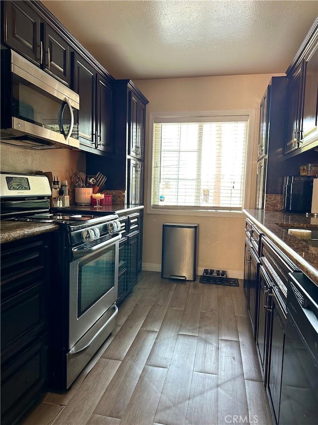 14811 Alexander St, San Fernando, CA 91345 - kitchen featuring appliances with stainless steel finishes, wood finished floors, dark countertops, and a textured ceiling