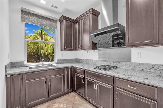 65 Rexford, Irvine, CA 92620 - kitchen with wall chimney exhaust hood, stainless steel gas stovetop, dark brown cabinetry, light stone counters, and light tile patterned flooring
