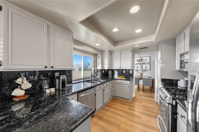 747 Highland View Dr, Corona, CA 92882 - kitchen with appliances with stainless steel finishes, a tray ceiling, backsplash, white cabinets, and light wood-type flooring