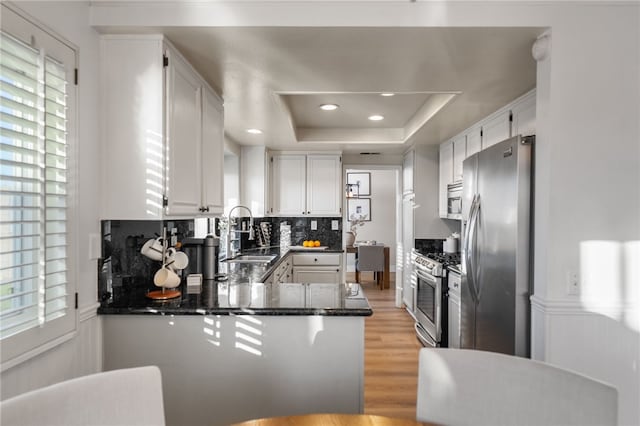 747 Highland View Dr, Corona, CA 92882 - kitchen with appliances with stainless steel finishes, a peninsula, tasteful backsplash, light wood finished floors, and a raised ceiling