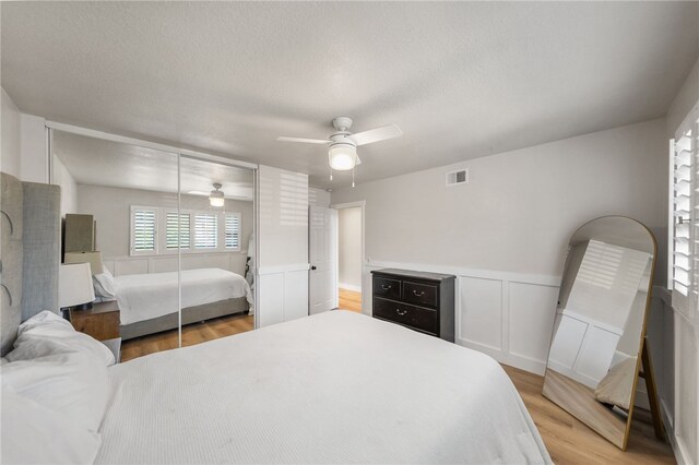 747 Highland View Dr, Corona, CA 92882 - bedroom with light wood finished floors, a ceiling fan, a wainscoted wall, and a textured ceiling