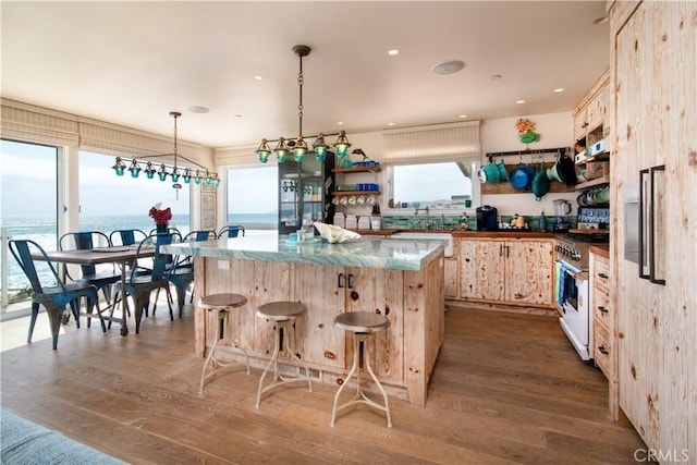 3436 Studio Dr, Cayucos, CA 93430 - kitchen featuring high end range, wood finished floors, a center island, a kitchen bar, and recessed lighting