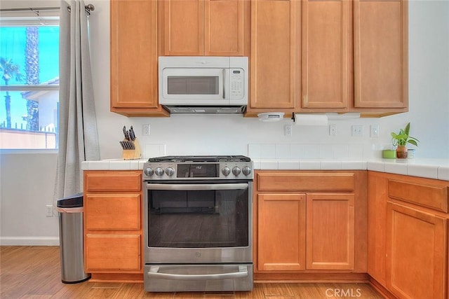 1503 Lynwood Way, Highland, CA 92346 - kitchen with white microwave, gas range, tile countertops, and light wood-style flooring