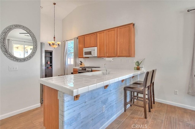 1503 Lynwood Way, Highland, CA 92346 - kitchen featuring white microwave, stainless steel range oven, light wood finished floors, a breakfast bar area, and high vaulted ceiling