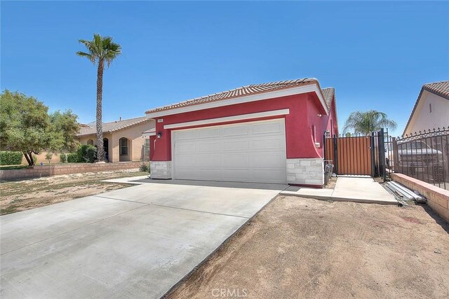 1503 Lynwood Way, Highland, CA 92346 - view of front of house with stone siding, a tiled roof, a gate, stucco siding, and a garage