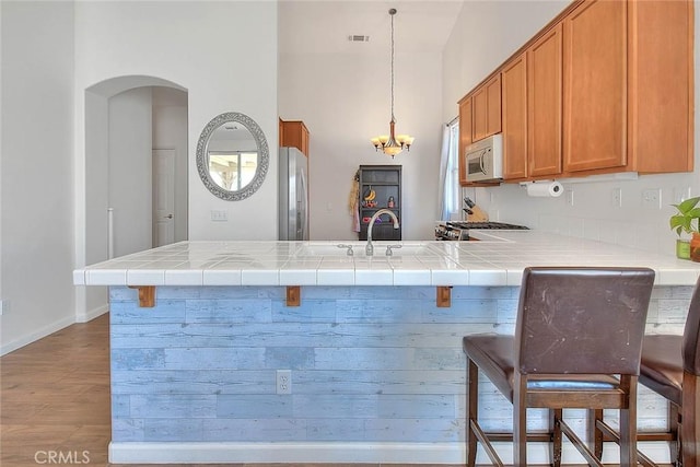 1503 Lynwood Way, Highland, CA 92346 - kitchen with a peninsula, brown cabinets, wood finished floors, arched walkways, and range