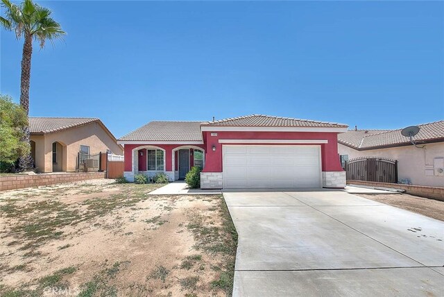 1503 Lynwood Way, Highland, CA 92346 - mediterranean / spanish home featuring an attached garage, concrete driveway, a tiled roof, a gate, and stucco siding