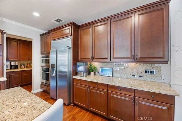 22517 Skipping Stone Dr, Saugus, CA 91350 - kitchen with appliances with stainless steel finishes, dark wood-type flooring, decorative backsplash, ornamental molding, and light stone countertops