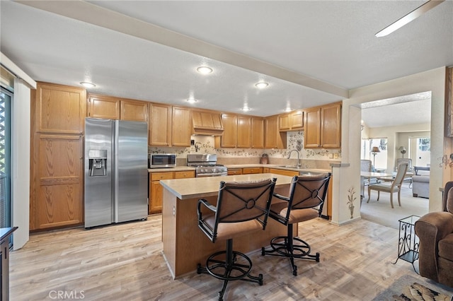 11361 Foxglove Ln, Corona, CA 92878 - kitchen with appliances with stainless steel finishes, light countertops, a kitchen island, light wood-style floors, and recessed lighting