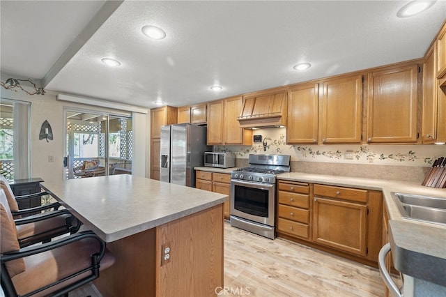 11361 Foxglove Ln, Corona, CA 92878 - kitchen featuring stainless steel appliances, a kitchen bar, light wood finished floors, light countertops, and a center island