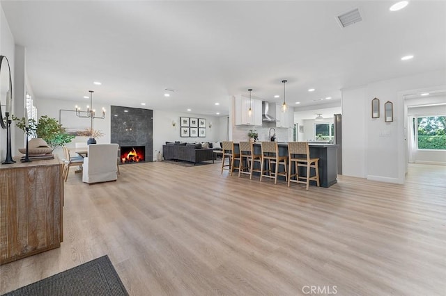 927 E Fairway Dr, Orange, CA 92866 - kitchen with white cabinets, light wood-style floors, a kitchen bar, recessed lighting, and wall chimney exhaust hood