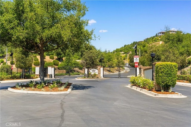16389 Viewcrest Rd, Chino Hills, CA 91709 - view of asphalt road with a gate, curbs, a gated entry, traffic signs, and street lights