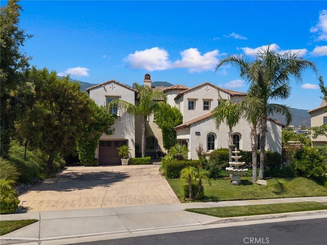 5231 Flora Ct, Rancho Cucamonga, CA 91739 - mediterranean / spanish-style house with stucco siding, decorative driveway, a chimney, and a garage