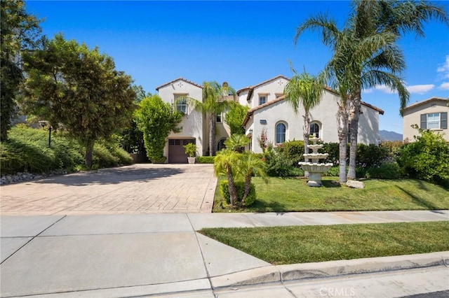 5231 Flora Ct, Rancho Cucamonga, CA 91739 - mediterranean / spanish-style house featuring decorative driveway, a front lawn, stucco siding, and an attached garage