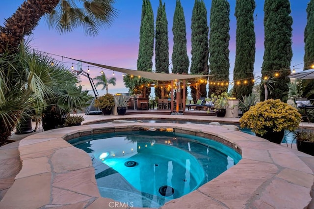 24630 Kittridge St, West Hills, CA 91307 - pool at dusk featuring an outdoor pool, an in-ground hot tub, and a patio
