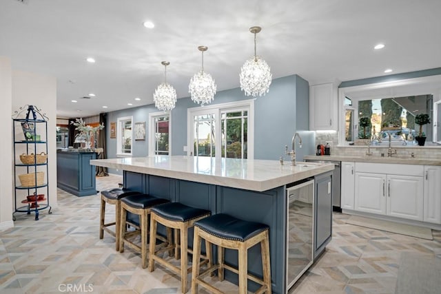 24630 Kittridge St, West Hills, CA 91307 - kitchen featuring wine cooler, recessed lighting, a chandelier, a kitchen island with sink, and white cabinets