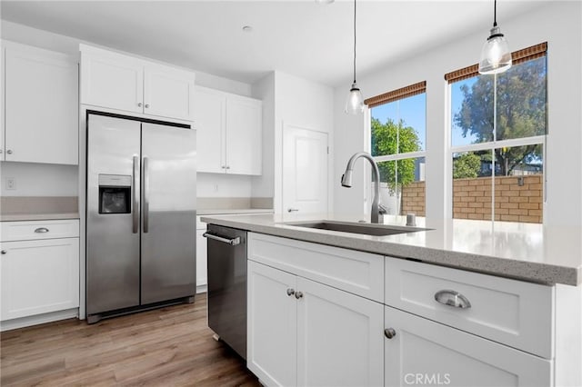 403 Aura Dr, Costa Mesa, CA 92626 - kitchen featuring stainless steel appliances, white cabinets, hanging light fixtures, light wood-type flooring, and light stone counters