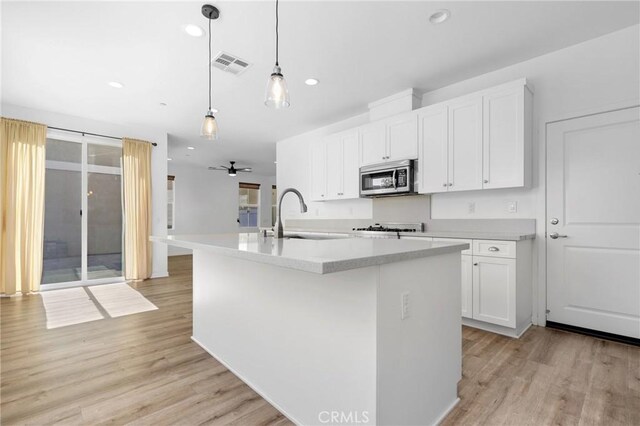 403 Aura Dr, Costa Mesa, CA 92626 - kitchen featuring stainless steel microwave, light wood-type flooring, white cabinetry, a kitchen island with sink, and a ceiling fan