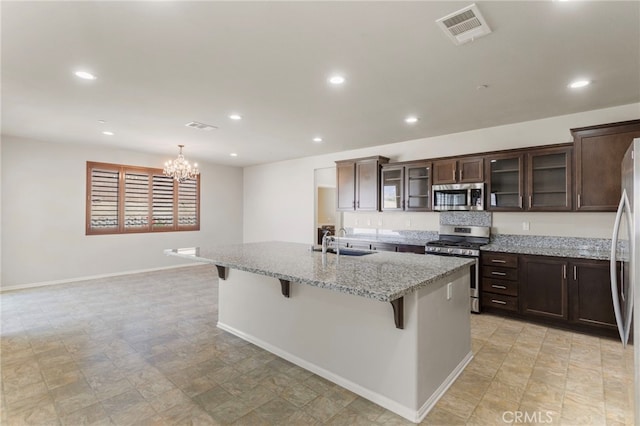11462 Jacobsen Rd, Beaumont, CA 92223 - kitchen featuring stainless steel appliances, a breakfast bar area, dark brown cabinets, a kitchen island with sink, and recessed lighting
