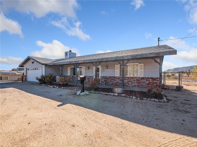 7423 Palomar Ave, Yucca Valley, CA 92284 - ranch-style house featuring an attached garage, covered porch, driveway, a chimney, and brick siding