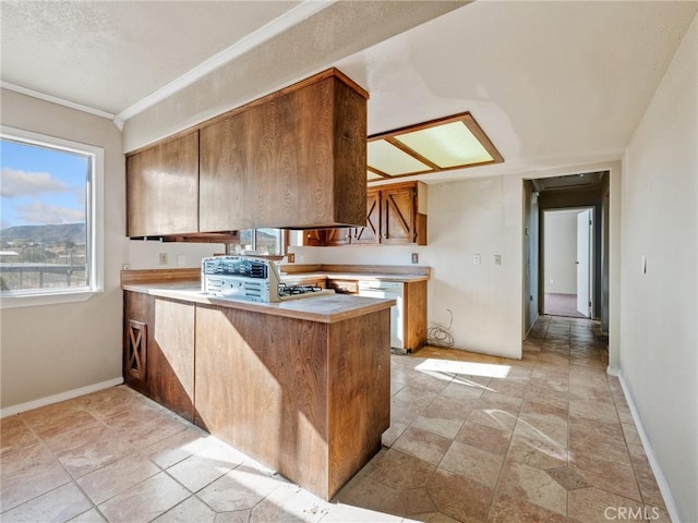 7423 Palomar Ave, Yucca Valley, CA 92284 - kitchen with a peninsula, white dishwasher, light countertops, brown cabinetry, and ornamental molding