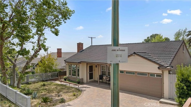 3348 Burritt Way, La Crescenta, CA 91214 - rear view of property featuring a chimney, a tiled roof, a garage, stucco siding, and decorative driveway