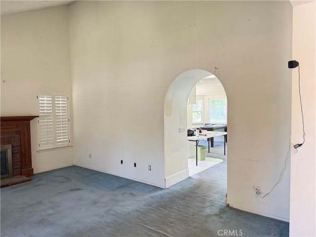 23020 Jensen Ct, Grand Terrace, CA 92313 - unfurnished living room featuring carpet flooring, arched walkways, and a brick fireplace