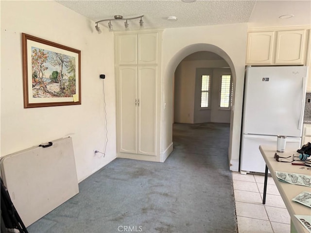 23020 Jensen Ct, Grand Terrace, CA 92313 - kitchen featuring freestanding refrigerator, arched walkways, a textured ceiling, light carpet, and rail lighting