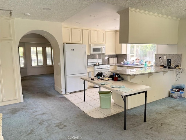 23020 Jensen Ct, Grand Terrace, CA 92313 - kitchen with white appliances, light carpet, arched walkways, a peninsula, and a textured ceiling