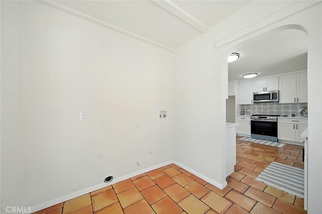 1123 W 81st St, Los Angeles, CA 90044 - kitchen with stainless steel appliances, arched walkways, tasteful backsplash, white cabinetry, and light countertops