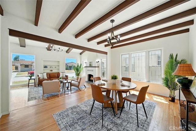 1123 W 81st St, Los Angeles, CA 90044 - dining area with a chandelier, light wood finished floors, a lit fireplace, and beam ceiling