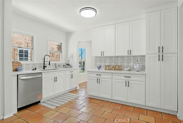 1123 W 81st St, Los Angeles, CA 90044 - kitchen featuring dishwasher, light countertops, tasteful backsplash, white cabinetry, and arched walkways