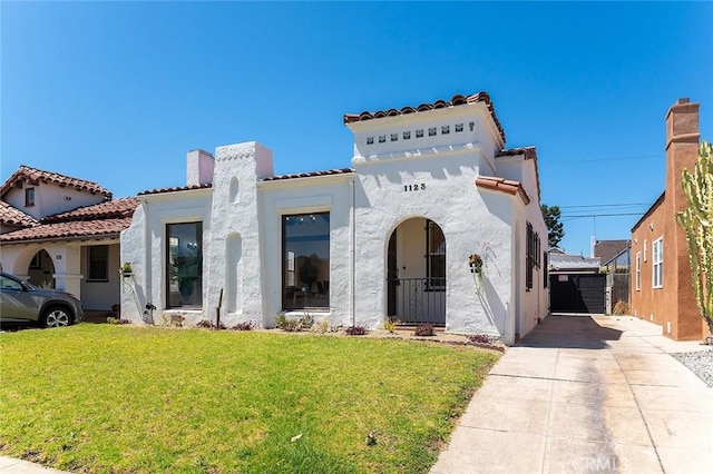 1123 W 81st St, Los Angeles, CA 90044 - mediterranean / spanish home with a front yard, stucco siding, driveway, a chimney, and a tile roof