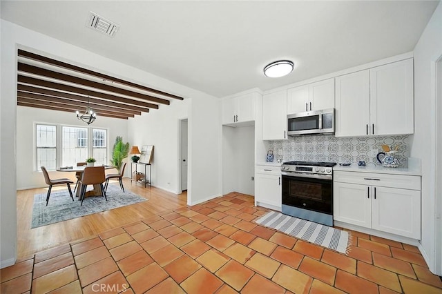 1123 W 81st St, Los Angeles, CA 90044 - kitchen with appliances with stainless steel finishes, backsplash, light countertops, white cabinetry, and beamed ceiling