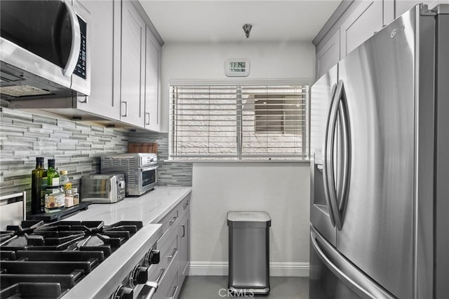5230 Zelzah Ave Unit 3, Encino, CA 91316 - kitchen with stainless steel appliances, gray cabinetry, decorative backsplash, and light stone countertops
