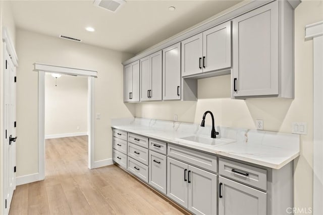 5035 San Juanico Dr, Chico, CA 95973 - kitchen with light wood-type flooring, gray cabinetry, light stone countertops, and recessed lighting