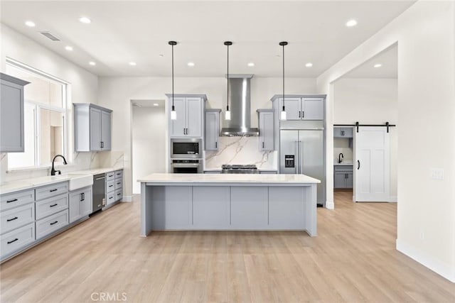 5035 San Juanico Dr, Chico, CA 95973 - kitchen featuring gray cabinets, wall chimney range hood, built in appliances, a kitchen island, and decorative backsplash