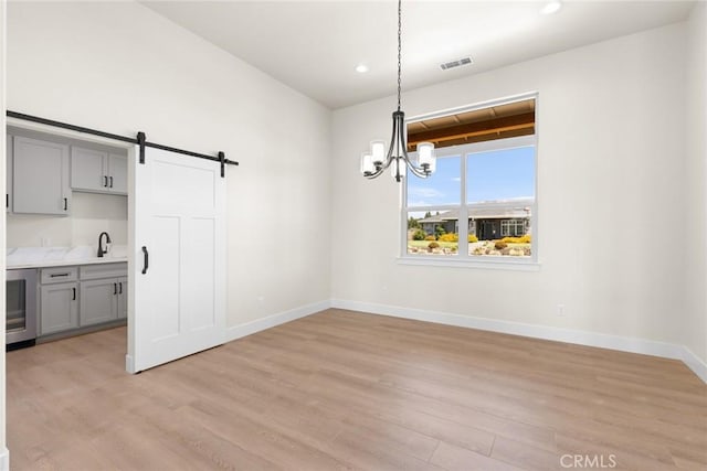 5035 San Juanico Dr, Chico, CA 95973 - unfurnished dining area with light wood finished floors, a chandelier, a barn door, and recessed lighting