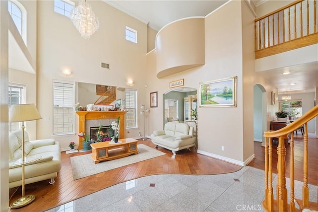 5939 N Vista St, San Gabriel, CA 91775 - living room featuring arched walkways, crown molding, a chandelier, a towering ceiling, and a glass covered fireplace