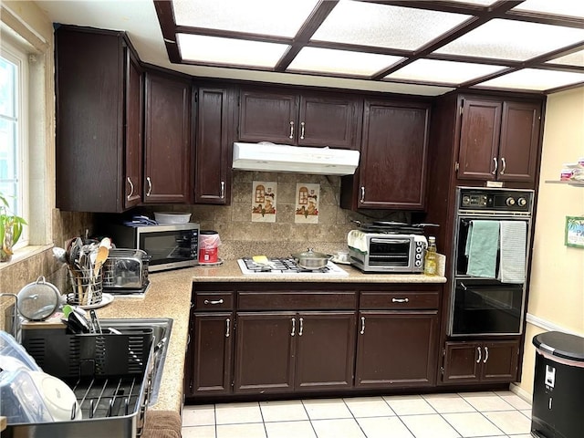 1061 N Perris Blvd, Perris, CA 92571 - kitchen featuring under cabinet range hood, white gas cooktop, light countertops, stainless steel microwave, and dark brown cabinets